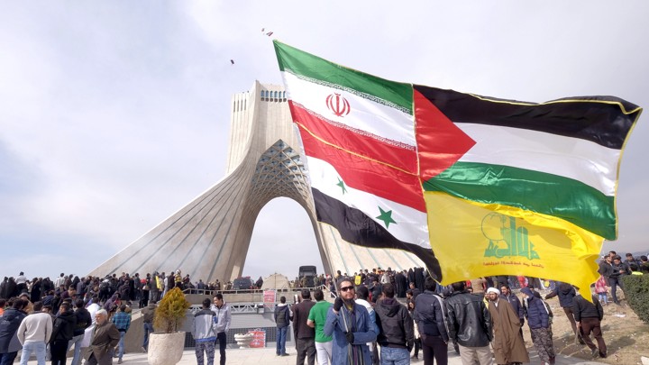 A man carries a giant flag made of flags of Iran, Palestine, Syria and Hezbollah, during a ceremony marking the 37th anniversary of the Islamic Revolution, in Tehran February 11, 2016. REUTERS.